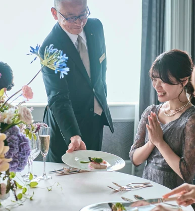 写真：運ばれる料理に喜ぶ参列者